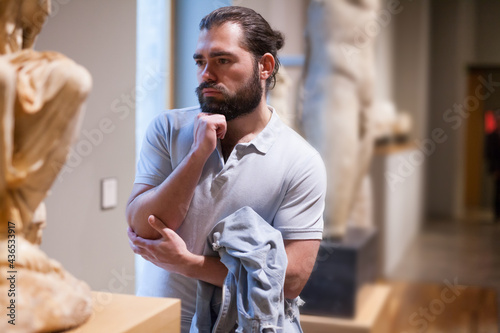 Man looking at stone architectural elements in historical museum hall. High quality photo