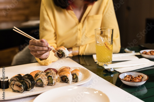 Sushi Japanese food close-up with woman hand in a restaurant. Lifestyle sashimi tasty seafood and rice rolls. Yellow color of the year photo