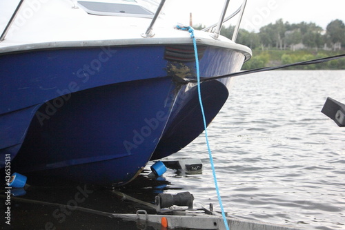 Motor boat launch, plastic watercraft bow keel and trailer under water on slip way closeup front side view at summer day
