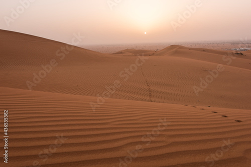 Beautiful desert sunrise with sun visible and sand dooms with sand pattern & walk path