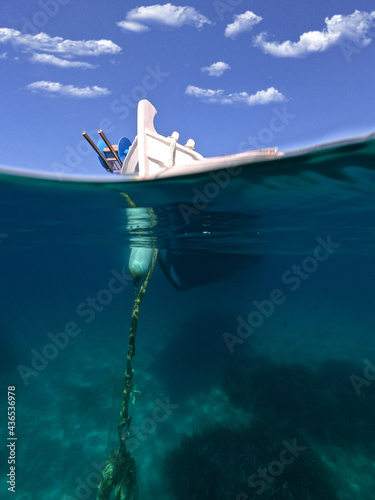 Underwater split photo of traditional fishing boat anchored near deep blue sea of picturesque port of Naousa, Paros island, Cyclades, Greece