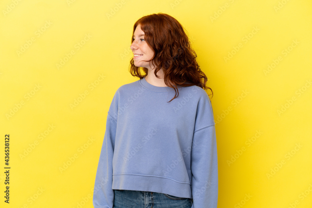 Teenager reddish woman isolated on yellow background looking side Teenager reddish woman isolated on yellow background looking side