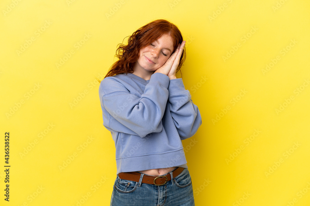 Teenager reddish woman isolated on yellow background making sleep gesture in dorable expression Teenager reddish woman isolated on yellow background making sleep gesture in dorable expression