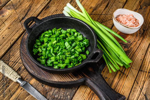 Sliced Green onions in a pan. wooden background. Top view