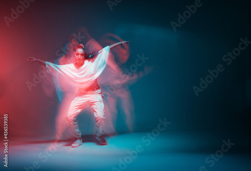 Contemporary hip hop dance. Cool dancing modern girl moving in colorful neon studio light. Long exposure. Copy space.