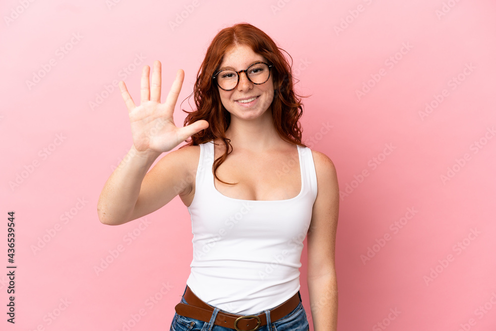 Teenager reddish woman isolated on pink background counting five with fingers