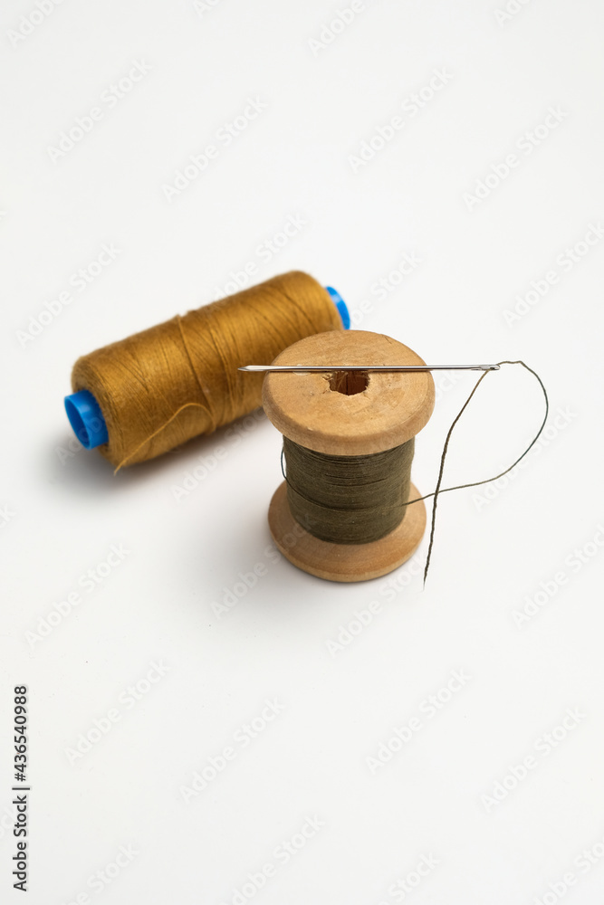 wooden reels with thread on a solid background.