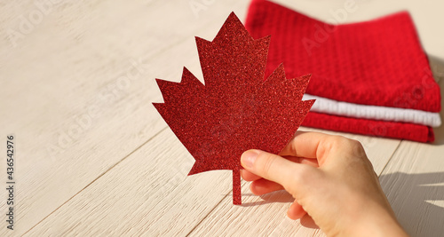 Red maple leaf made of paper in the hand, table setting background. Happy Canada Day. Copy space