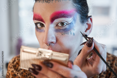 Obraz na płótnie Drag queen with long nails applying eye shadows at his eyelids