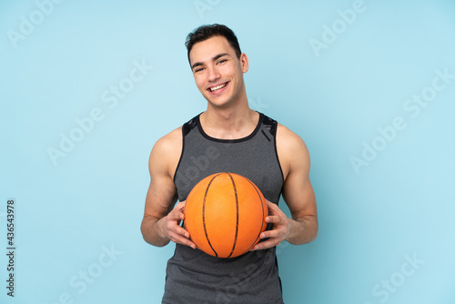 Man on isolated blue background playing basketball © luismolinero