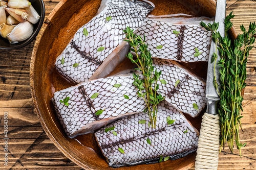 Cut Raw grenadier macrurus white fish without head in a wooden plate. Wooden background. Top view photo