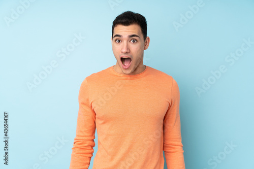 Young caucasian handsome man isolated on blue background with surprise facial expression