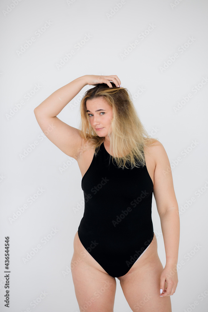 Beautiful overweight woman in black swimsuit on grey background Beautiful overweight woman in black swimsuit on grey background