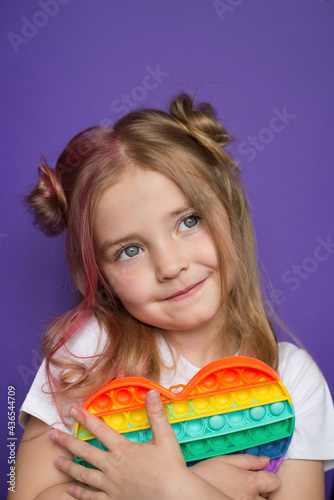 a baby girl holds a popular pop it toy in her hands. Sensory game for training with a neuropsychologist, for people with autism, for the development of fine motor skills