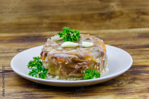 Meat aspic in a plate on a wooden table. Traditional russian dish photo