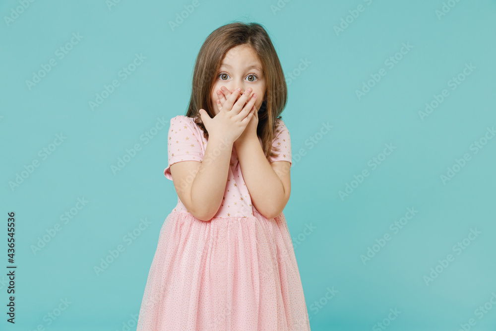 Little shocked surprised fun cute kid girl 5-6 years old wears pink dress cover mouth isolated on pastel blue color background child studio portrait. Mother's Day love family people lifestyle concept. Little shocked surprised fun cute kid girl 5-6 years old wears pink dress cover mouth isolated on pastel blue color background child studio portrait. Mother's Day love family people lifestyle concept.