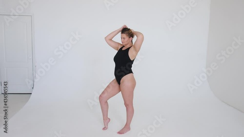 Beautiful overweight woman in black swimsuit on grey background