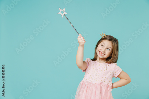 Little fun kid girl princess 5-6 years old wears pink dress crown diadem hold magic wand fairy stick isolated on pastel blue color background child studio. Mother's Day love family lifestyle concept.