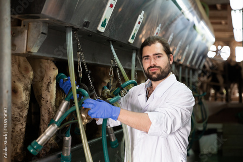 Portrait of experienced owner of dairy farm preparing for machine milking of cows