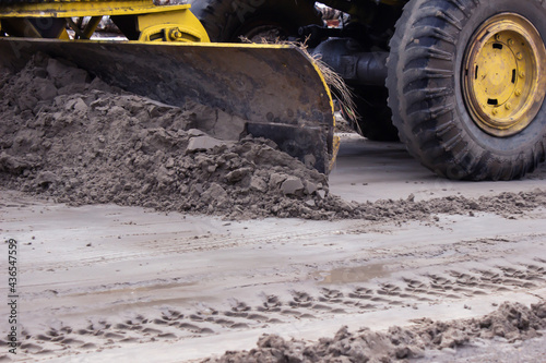 The grader levels the sandy road. Road construction works