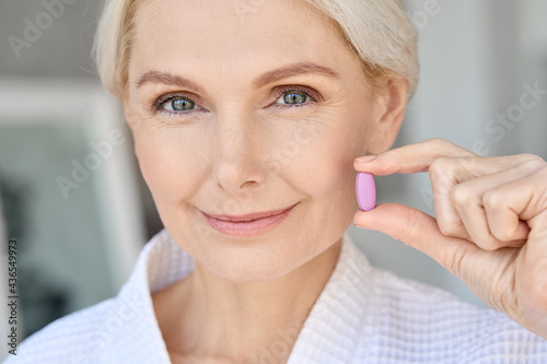Foto Closeup portrait of happy middle aged 50s woman holding pill taking dietary supplements