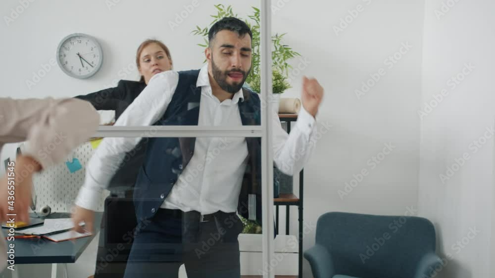 Handsome middle-aged guy in suit is dancing in office with coworkers having fun at work enjoying corporate party. Happiness and relaxation concept. Handsome middle-aged guy in suit is dancing in office with coworkers having fun at work enjoying corporate party. Happiness and relaxation concept.