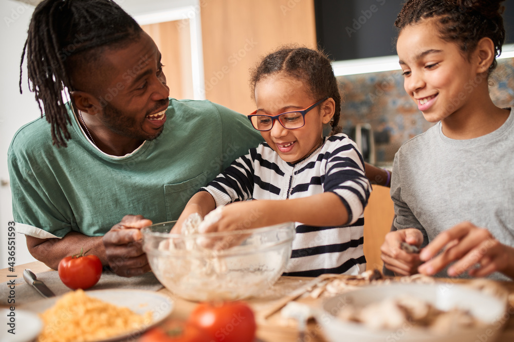 Parent and small multiracial children preparing pizza in kitchen