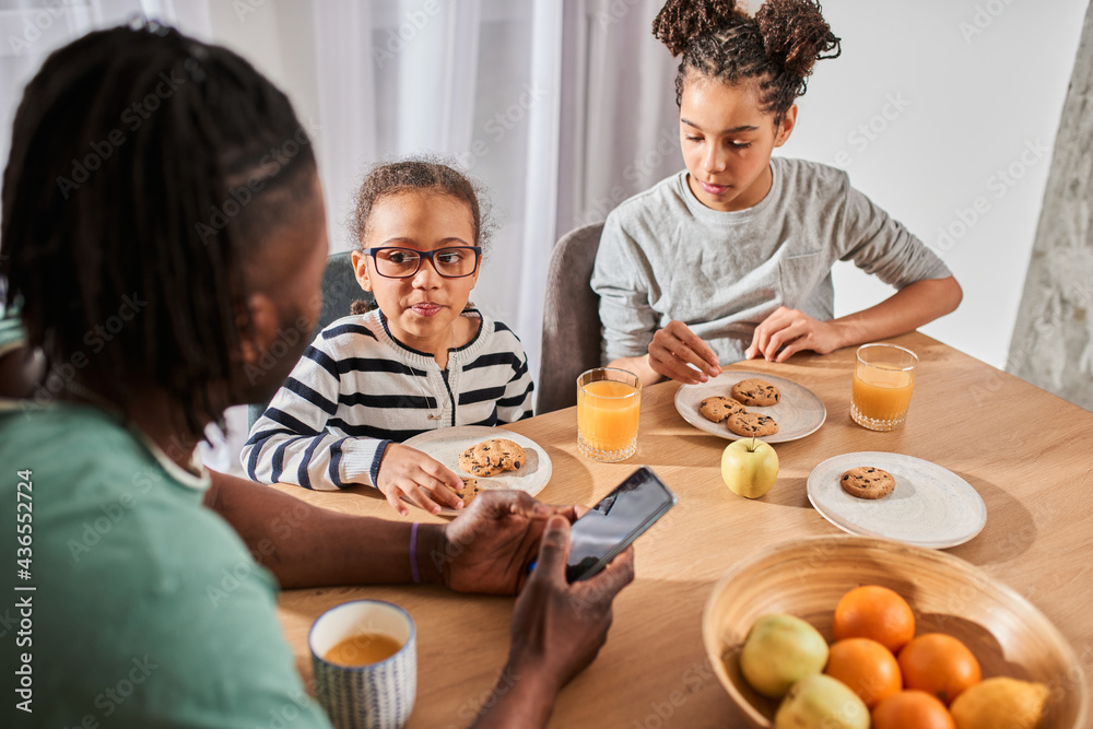 Children having breakfast with appetite and looking into their father Children having breakfast with appetite and looking into their father