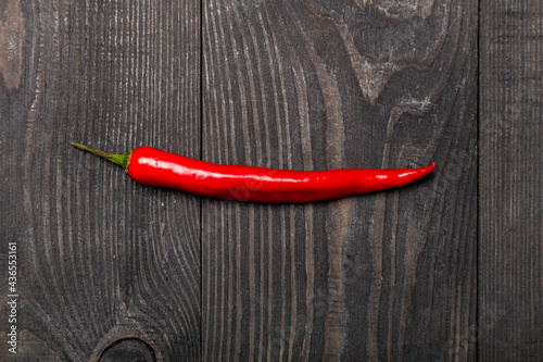 a pod of red hot chili pepper on wooden background