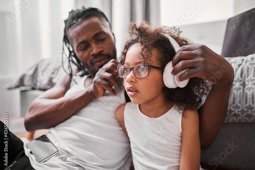 Father putting headphones on the head of his daughter