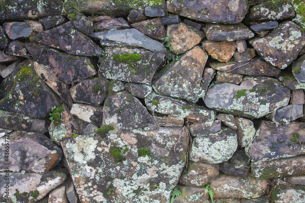 an old manmade stone wall with moss on it