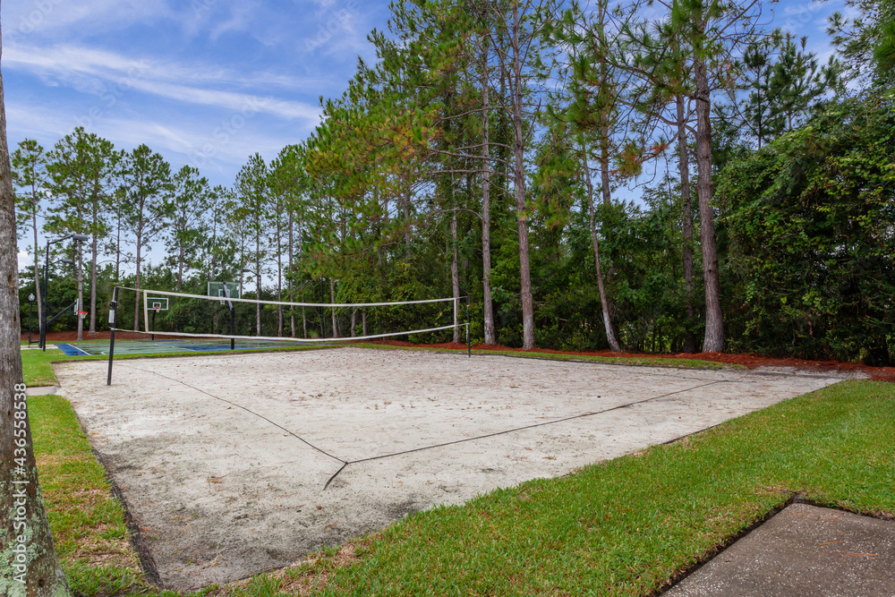 Beach volleyball court in a park surrounded by trees