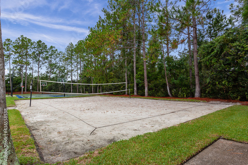 Beach volleyball court in a park surrounded by trees
