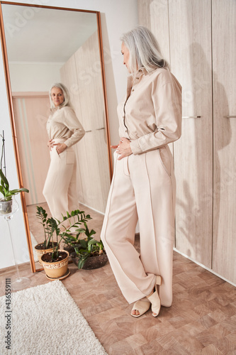 Canvas-taulu Woman looking at the mirror at her reflection while trying on new clothes