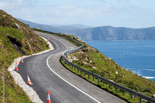Small narrow road by the ocean, Achill Island, county Mayo, Ireland. Warm sunny day. Irish landscape. Blue clear cloudy sky. Spectacular view