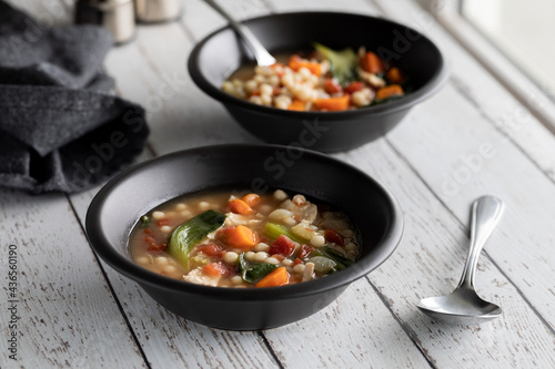 Two bowls of chicken and vegetable with couscous soup, ready for eating.