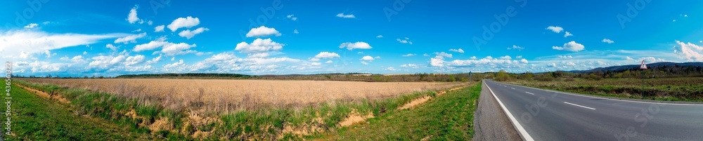 Panorama of plowed field in spring on a background of green mountains