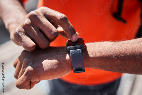 Male courier standing and looking at smartwatch during delivering