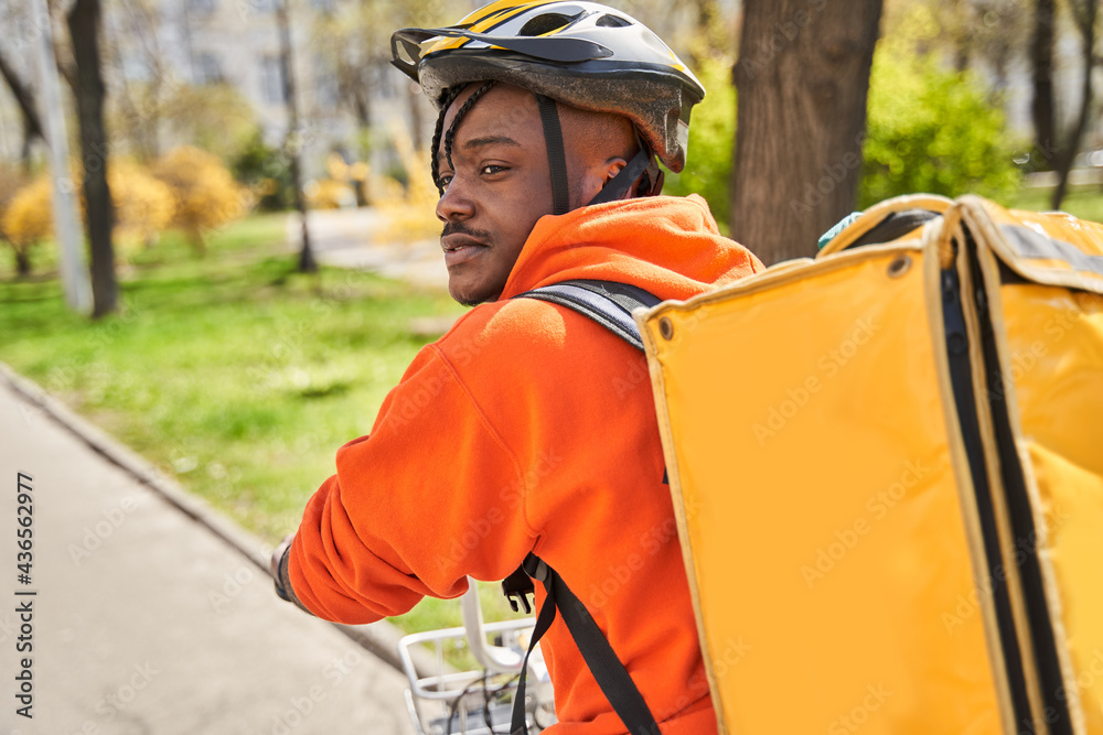 Courier wearing helmet walking with bicycle on the city street Courier wearing helmet walking with bicycle on the city street