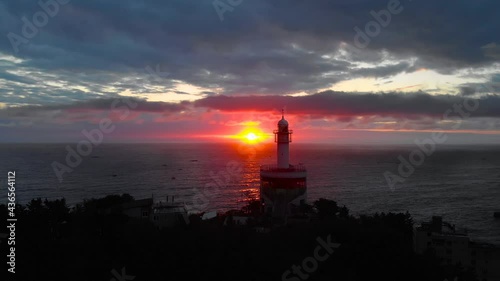 Lighthouse at sunrise of east coast sea of Korea. Sun is glowing red and  gold and clouds are turning reddish. Beautiful nature and landmark aerial drone footage took with 4K 30fps.