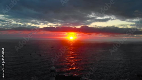 Lighthouse at sunrise of east coast sea of Korea. Sun is glowing red and  gold and clouds are turning reddish. Beautiful nature and landmark aerial drone footage took with 4K 30fps.