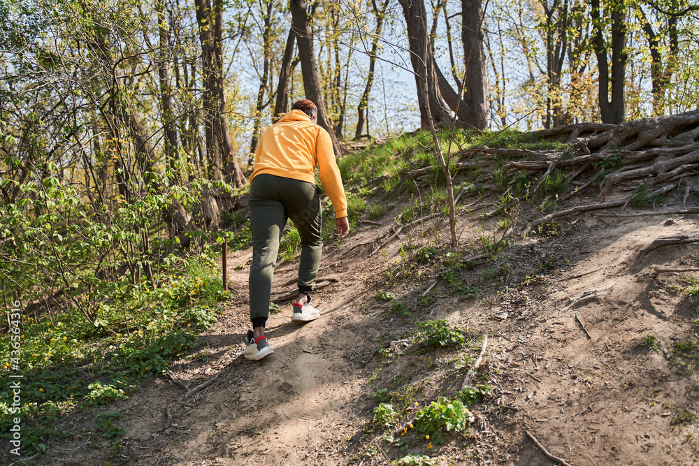 Man going uphill while walking at the forest or park Man going uphill while walking at the forest or park