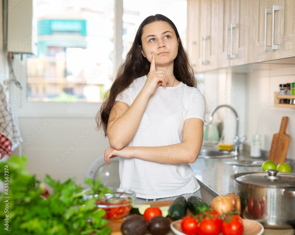 Attractive young housewife posing indoors in her modern clean stylish kitchen interior