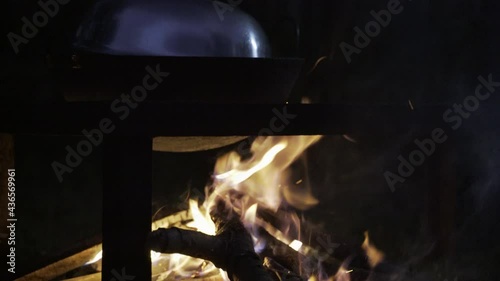 Chulha fire is stoked below large covered wok in rural Indian cooking photo