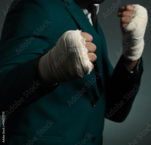 Closeup male hand of businessman fighter in suit with bandages and clenched fists.