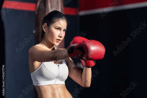 Sport girl Boxer athlete wear boxing glove and punch in fitness gym © Kawee
