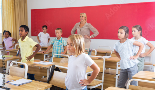 Group of smiling kids pupils of elementary school having physical training during lesson