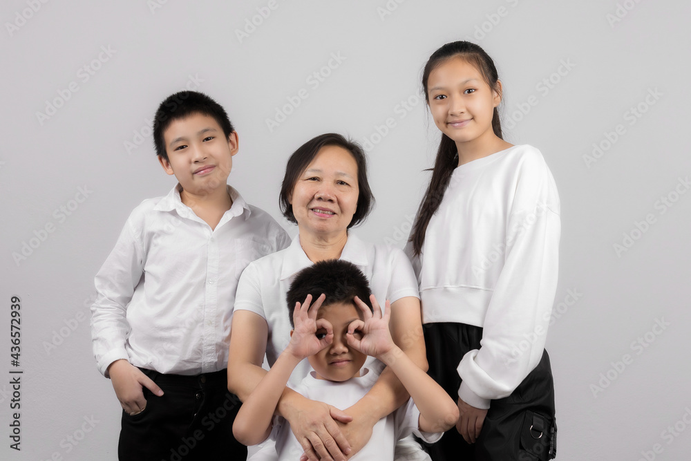 Portrait of Grandmother and grandchild hugging, looking at camera and smiling, on gray background Portrait of Grandmother and grandchild hugging, looking at camera and smiling, on gray background