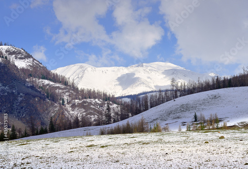 Snow in the Altai Mountains. Spring snow on the mountain slopes, the Kurai range in the distance under a cloudy blue sky. Siberia, Russia © ArhSib