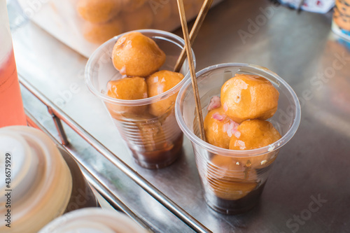 2 plastic cups filled with kwek kwek and fishball sauce. Deep fried Quail Eggs. photo